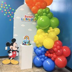 there is a bunch of balloons in front of the mickey mouse balloon arch at this birthday party