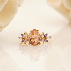 an orange diamond surrounded by white and purple stones sits on a table next to flowers