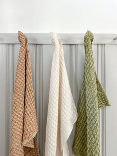 three different colored towels hanging on the wall in front of a white radiator