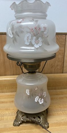 an old fashioned glass lamp with flowers on it