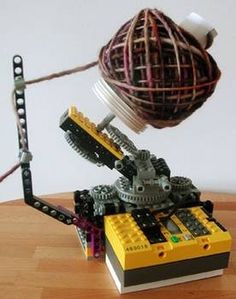 a toy made out of legos on top of a wooden table next to a ball of yarn