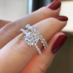 a woman's hand holding an engagement ring with two diamonds on the band and one diamond in the middle