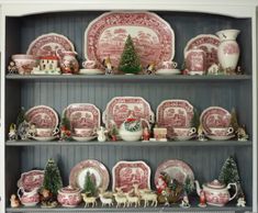 the china cabinet is filled with pink and white plates, dishes, and christmas decorations