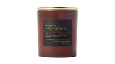 a candle that is sitting on top of a white surface with the words rustic palo sano written in gold