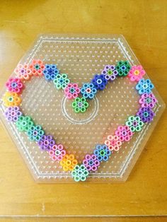 a heart shaped beaded object sitting on top of a plastic tray covered in beads