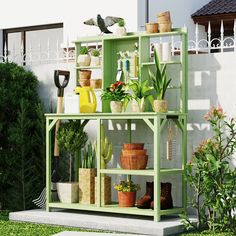 a green shelf filled with potted plants next to a white fence and grass area