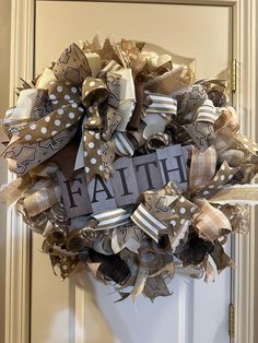 a wreath with the word faith on it is hanging on a front door, decorated with ribbons and bows