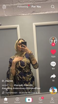 a woman taking a selfie in front of a mirror wearing a hijab