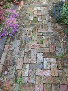 an old brick path with potted plants and flowers