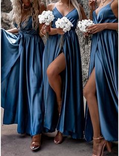 three women in blue dresses standing next to each other and one has her legs crossed