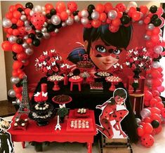 a red table topped with lots of desserts and balloons in the shape of ladybugs