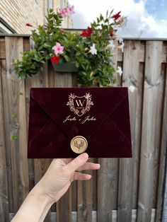 a person holding up an envelope with a wax stamp on it and a gold coin