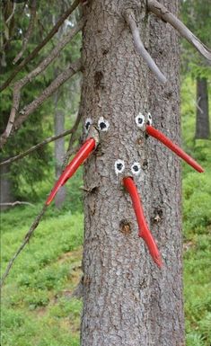 two red handled scissors are stuck to the side of a tree with googly eyes