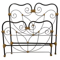 a wrought iron bed frame with gold flowers on the headboard and foot board, against a white background