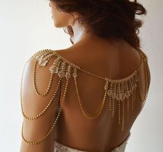 the back of a woman's dress with gold beading and chains on it