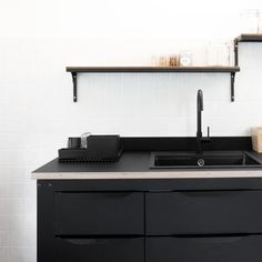 a kitchen with black cabinets and shelving on the wall above it is also a sink