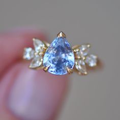 a blue and white diamond ring in someone's hand