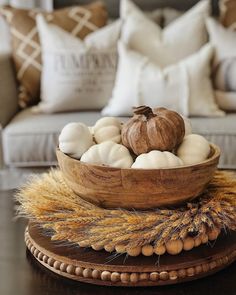 a wooden bowl filled with white balls on top of a table next to a couch