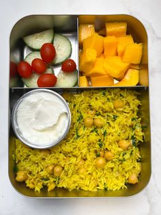 a metal container filled with rice and veggies next to cucumber slices