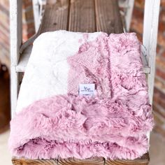 a pink and white blanket sitting on top of a wooden bench