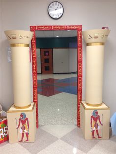 an egyptian themed hallway with two columns and a clock on the wall behind it,