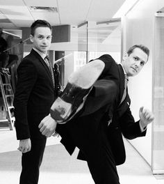 two men in suits and ties are posing for the camera with a skateboard on their feet