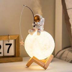 an astronaut lamp sitting on top of a wooden stand next to a clock and other items