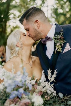 a bride and groom kissing in the woods