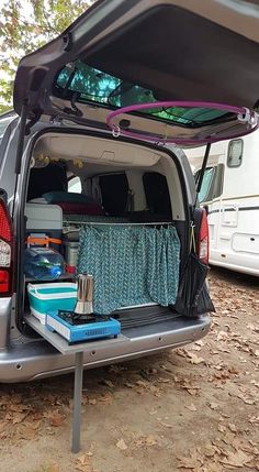 the back end of a van with its trunk open and various items in it sitting on the ground