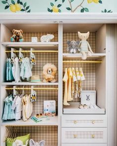 a baby's closet with lots of clothes and toys on shelves next to a wall mural