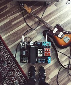 a person standing next to a guitar and other musical equipment on the floor in front of a tv