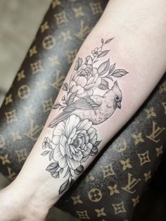 a bird and flowers tattoo on the arm