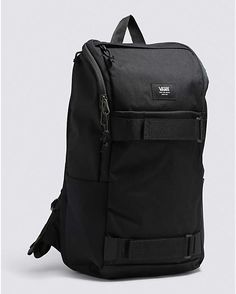 a black backpack sitting on top of a white floor next to a gray wall with the words vans written on it