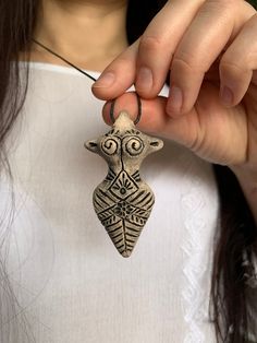 a woman is holding up a pendant with an owl on it