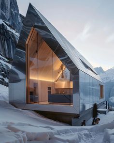 a person walking in the snow next to a building with glass walls and a roof