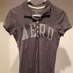 Aeropostale Button Down T-Shirt With A Collar. Gray. Never Worn. Great Condition. Juniors Medium. Aero Stitched On The Front. Collared Cotton T-shirt With Letter Print, Cotton Button-up Tops With Letter Print, Collared Cotton Tops With Letter Print, Cotton Collared T-shirt With Letter Print, Fitted Cotton Button-up T-shirt, Casual Cotton Polo Shirt With Letter Print, Fitted Short Sleeve Polo Shirt With Letter Print, Basic Cotton T-shirt With Button Closure, Casual Cotton Polo Shirt With Buttons