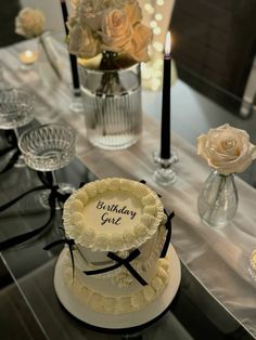 a birthday cake sitting on top of a table next to candles and vases filled with flowers