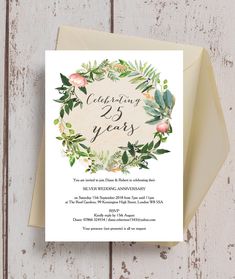 a card with the words celebrating 25 years and floral wreath on it, against a wooden background