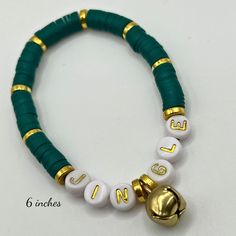 a green and white beaded bracelet with gold bells on the clasp, which says love