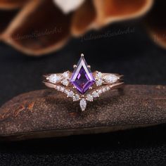 an engagement ring with a purple and white diamond in the center on top of a rock