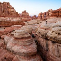 a man standing on top of a large rock formation in the middle of a desert