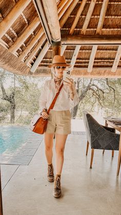 a woman walking under a thatched roof with her cell phone up to her ear