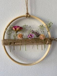 an embroidery hoop with flowers hanging from it