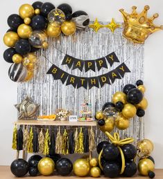 a birthday party with black and gold balloons, streamers and foil tassels