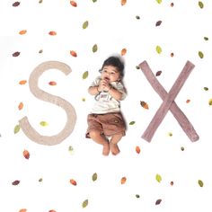 a young child laying on the ground next to letters that spell out s and x