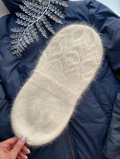 someone is holding their mitts up to the snowflake on top of them