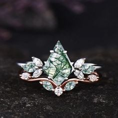 a close up of a ring with leaves and diamonds on it's sides, sitting on a black surface