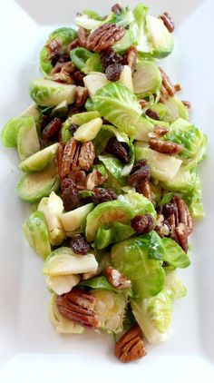 lettuce salad with pecans and cranberries on white platter, ready to be eaten