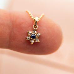 "Magen David - pendant necklace with blue sapphire and diamonds, A Star of David necklace, crafted in 14k gold, a symbol of Jewish faith and heritage, a beautiful piece of Israeli Jewelry. This meaningful Magen David pendant necklace represents the enduring strength and spirit of the Jewish people. The 'Magen David' is an iconic symbol of Judaism, signifying its significance and unity. The blue sapphire signifies Israel's connection, and the gold and diamonds represent the beauty and strength of Elegant Star Of David Birthstone Jewelry, Sapphire Jewelry With Single Cut Diamonds For Gift, Sapphire Jewelry With Single Cut Diamonds As A Gift, Elegant Blue Jewelry With Star Charm, Elegant Blue Star Charm Jewelry, Star Of David Necklace With Single Cut Diamonds, Celestial Diamond Star Of David Jewelry, Sapphire Pendant With Single Cut Diamonds, Celestial Star Sapphire Jewelry