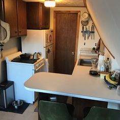 a kitchen with white counter tops and wooden cabinets in the back drop off from the ceiling